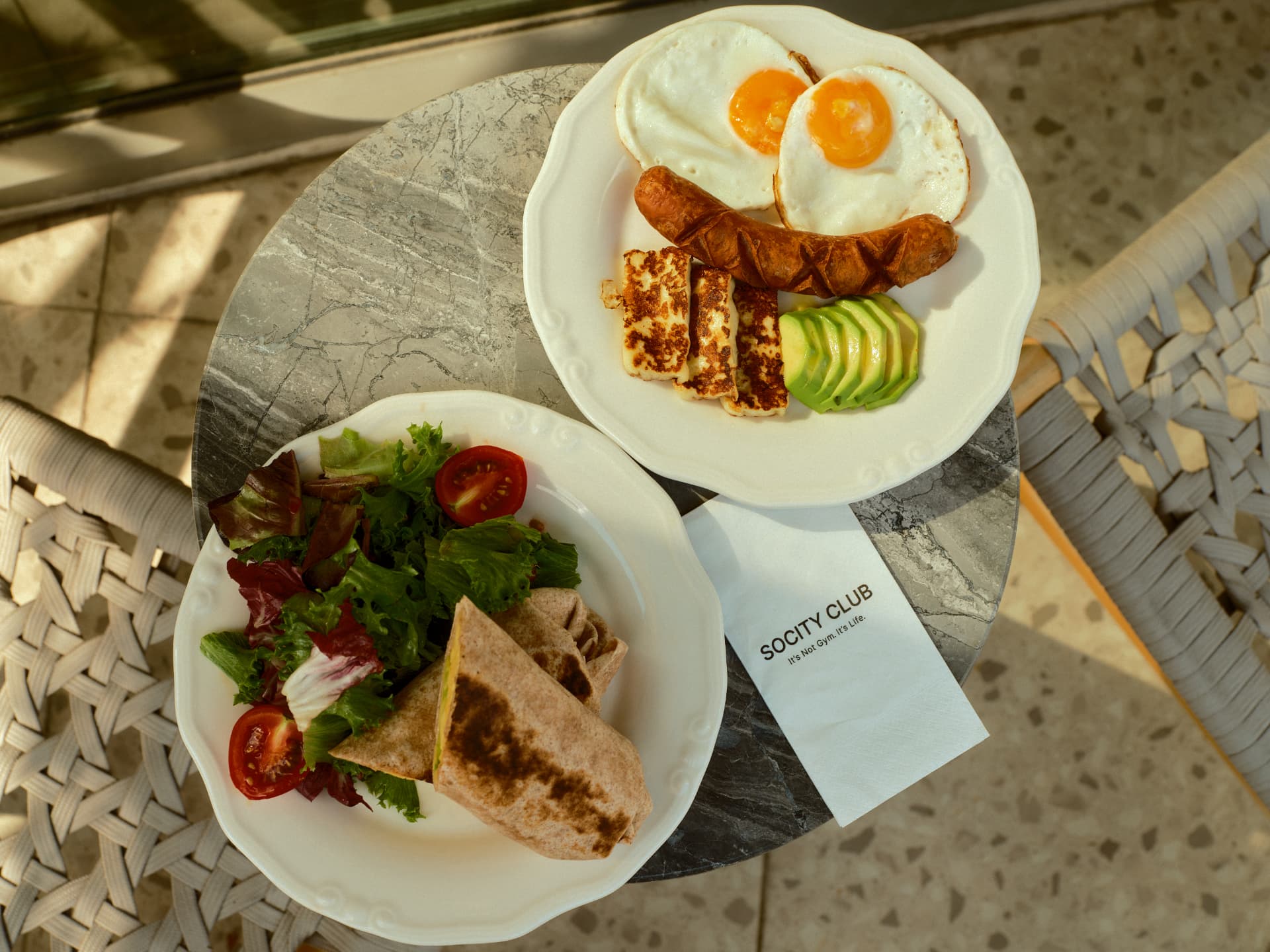 Breakfast plate with eggs, halloumi and a wrap with salad on the terrace